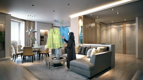 اختيار الملابس والتسوق بالتقنية والتكنولوجيا المستقبلية الحديثة, امرأة عربية خليجية سعودية محجبة ترتدي عباءة سوداء ونظارات الواقع الافتراضي تقف في منزلها تقوم بالتفاعل مع عناصر هولوجرامية ثلاثية الأبعاد، رؤية مستقبيلة سعودية 2032