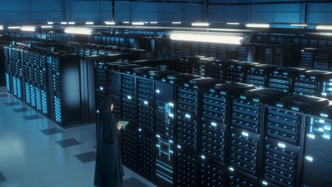 غرفة التحكم بالسيرفرات وخوادم الانترنت، تسهيل الوصول للمعلومات والبيانات من خلال نظم قواعد البيانات، امرأة عربية خليجية سعودية ترتدي الحجاب والعباءة تقوم بالتحكم بالمواقع المستضافة على السيرفرات من خلال جهاز التابلت
