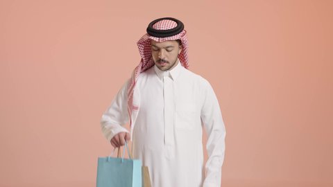 شراء المستلزمات و الهدايا, التسوق والحصول على العروض, بورتريه لشاب عربي خليجي سعودي يرتدي الثوب التقليدي و الشماغ  يقوم بالتبضع وأخذ الاحتياجات اللازمة, الاستفادة من مواسم الحسومات والتصفيات