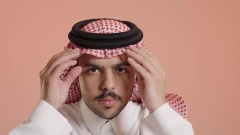 مفهوم الشياكة والأناقة والرجولة ، بورتريه لشاب عربي خليجي سعودي يرتدي الثوب التقليدي يقوم بتعديل الشماغ، ايماءات السرور و التركيز، الاهتمام بالمظهر الخارجي