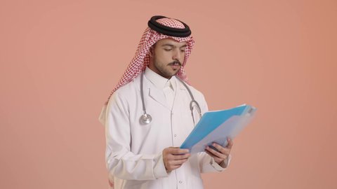 مفهوم الرعاية الصحية في السعودية، بورتريه لطبيب عربي خليجي سعودي يرتدي الثوب التقليدي والشماغ والسماعة الطبية يقوم بقراءة ملف, تقديم الخدمات العلاجية في المراكز الطبية والمستشفيات