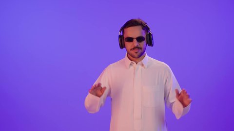 استخدام الأجهزة التكنولوجية، بورتريه لرجل عربي خليجي سعودي يرتدي الثوب التقليدي و نظارة شمسية و  يضع سماعة على أذنه، الإستماع الى الموسيقى, الاستمتاع بتقنية الهيدفون, ايماءات وجه ويدين تدل على الرقص والتفاعل مع الأغاني