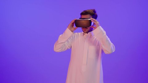 التفاعل ومحاكاة العالم الخيالي، بورتريه لرجل عربي خليجي سعودي يرتدي الثوب الأبيض التقليدي يقوم بمشاهدة أفلام عبر نظارات الواقع الإفتراضي، الأجهزة والتقنيات الحديثة والمتطورة، لعب ألعاب الفيديو ثلاثية الأبعاد
