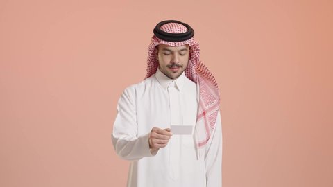 التعبير عن الذات، إبراز الهوية الشخصية، بورتريه لشاب عربي خليجي سعودي يرتدي الشماغ والثوب التقليدي و يمسك بيده بطاقة بيضاء فارغة  ينظر الى الكاميرا بايماءات السرور