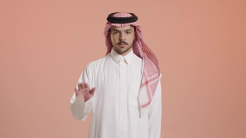 مفهوم الامتناع والانزعاج, طلب التوقف وعدم الاقتراب, بورتريه لشاب عربي خليجي سعودي يرتدي الشماغ والثوب التقليدي يرفع يده للأعلى بإيماءات الرفض, عدم الإعجاب وعدم قبول شيء ما