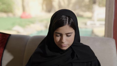 دمج التكنولوجيا الحديثة بالحياة العملية، ايماءات الاندماج و التركيز، صناعة المحتويات النصية، مفهوم ادخال البيانات،تصويرلامراة عربية خليجية سعودية تجلس فى غرفه المعيشة و تستخدم الحاسوب المحمول، الكتابة على جهازاللابتوب