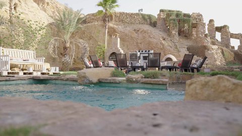 مسبح خارجي محاط بالنخيل والمجالس التراثية، تصميم فني لمنتجع سياحي، أجواء استرخاء في الهواء الطلق
