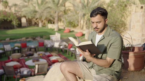 التزود بالعلم والمعرفة، ممارسة هواية المطالعة، مفهوم الثقافة والاطلاع والتعلم الذاتي, تصوير لشاب عربي خليجي سعودي يرتدي الزي الكاجوال يقوم بالقراءة والمطالعة في الهواء الطلق، أماكن هادئة و مريحة للدراسة