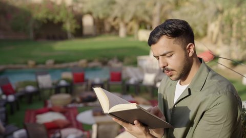 ممارسة هواية المطالعة، قضاء وقت الفراغ بالتثقيف والتعلم,، مفهوم الثقافة والاطلاع والتعلم الذاتي, تصوير لشاب عربي خليجي سعودي يرتدي الزي الكاجوال يقوم بالقراءة والمطالعة في الهواء الطلق
