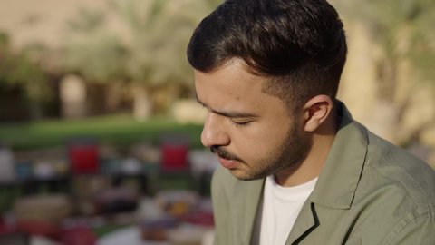 الأنشطة الترفيهية الثقافية، الشغف بممارسة الهوايات المفيدة، مفهوم الثقافة والاطلاع والتعلم الذاتي, تصوير مقرب لشاب عربي خليجي سعودي يرتدي الزي الكاجوال يقوم بالقراءة والمطالعة في الهواء الطلق