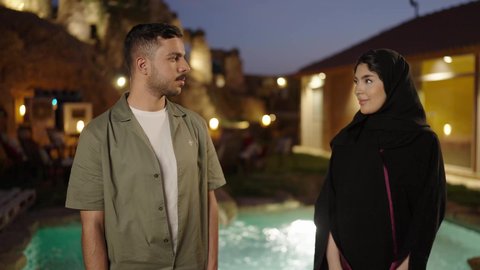 Expressions of self-confidence, looking at the camera with gestures of happiness and joy, elegance and attention to appearance, a Saudi Arabian couple standing upright with arms crossed in the open air.