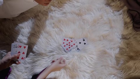 Group entertainment and having a good time, shuffling cards with professional moves, close-up shots of a Saudi Gulf Arab family playing a card game, engaging in fun activities and games.