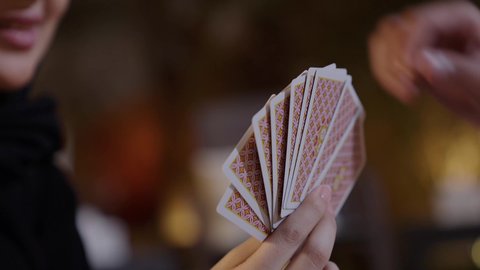 أجواء من الترفيه والمتعة مع الأصدقاء، خلط الأوراق بحركات احترافية، تصوير مقرب ليد امراة عربيه خليجيه سعودية ترتدي العباءه و الحجاب تقوم بالعب لعبه الورق ، مفهوم التركيز والتحدي في لعبة الكوتشين