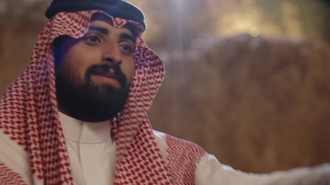 مفهوم التركيز و التحدي، تصويرمقرب لشاب عربي خليجي سعودي يرتدي الزي التقليدي و المشاغ يلعب لعبة الورق, أنشطه ترفيهيه ممتعة, قضاء وقت ممتع فى الخارج