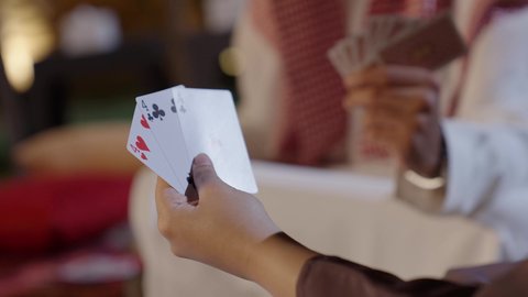 مفهوم التسلية وقضاء وقت ممتع، تصوير مقرب ليد امراة عربيه خليجيه سعودية تقوم باللعب بأوراق الكوتشينة، نشاط ترفيهي يجمع العائلة والأصدقاء