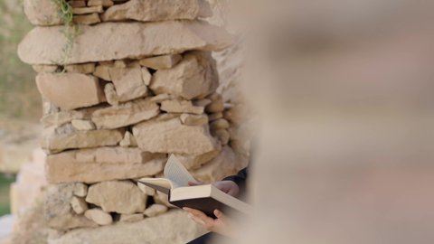 تمضية أوقات الفراغ بالتعلم والتثقيف الذات، قراءة الروايات والقصص، ايماءات التركيز والاستمتاع، ثقافة القراءة في أجواء تاريخية عربية, امرأة عربيه خليجيه سعودية ترتدي العباءة السوداء تستمتع بالقراءة بين الآثار القديمة