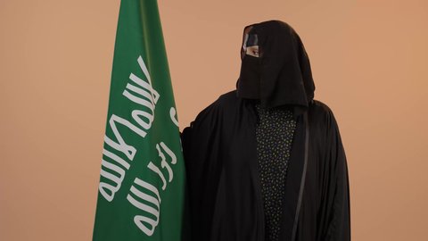 ذكرى تأسيس الدولة السعودية الأولى 1727م، الفخر بإنجازات المملكة، إظهار الولاء والحب للوطن, بورتريه لامرأة عربية خليجية سعودية ترتدي البرقع والعباءة تحمل علم التأسيس بإيماءات الاعتزاز والشموخ، يوم بدينا 22 فبراير، خلفية زهري