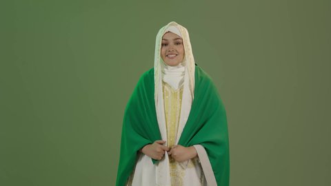 يوم العلم 11 مارس، شعار الهوية الوطنية وراية الإسلام والتوحيد، الأزياء الشعبية التقليدية، اليوم الوطني السعودي 23 سبتمبر، بورتريه لامرأة عربية خليجية سعودية مبتسمة ترتدي الشيلة والنشل تضع علم المملكة على كتفيها، ارتداء زي المنطقة الشرقية، خلفية خضراء، كروما