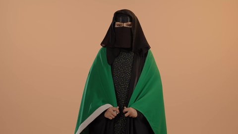 يوم العلم 11 مارس، الفخر والاعتزاز بالانتماء للبلاد، يوم بدينا22 فبراير, اليوم الوطني السعودي 23 سبتمبر، ارتداء الزي الشعبي في مناسبة وطنية، بورتريه لامرأة عربية خليجية سعودية ترتدي البرقع والعباءة تضع على كتفيهاعلم المملكة، خلفية زهرية