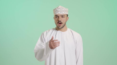 الإحساس بالكسل والخمول و الإرهاق, الشعور بالتعب والحاجة الى النوم والراحة، بورتريه لشاب عربي خليجي عماني يرتدي الدشداشة و الكمة يضع يده على فمه بإيماءات التثاؤب والنعاس، خلفية خضراء