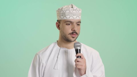 الدورات التدريبية و ورشات العمل, إلقاء المحاضرات وإقامة الندوات، تبادل الحوار والاستفادة من خبرات، بورتريه مقرب لرجل عربي خليجي عماني يرتدي الدشداشة والكمه  يحمل مكبر الصوت بيده ويقوم بالنقاشات الهامة، خلفية خضراء