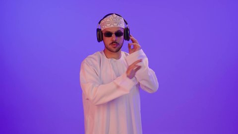 Artistic singing talents, gestures and expressions of immersion with the song, a portrait of an Arab Gulf Omani man wearing a dishdasha and kumma and sunglasses listening to music through headphones, gestures indicating attentiveness and listening to songs using headphones, interaction with musical rhythms, purple background.