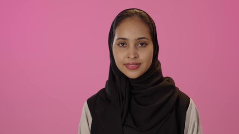 النظر الى الكاميرا بسعادة وسرور، علامة الجودة والإتقان، تعابير عن التميز والامتياز بإشارة لحالة ممتازة, بورتريه مقرب لشابة عربيه خليجيه سعودية سمراء محجبه ترتدي الزي الكاجوال تشير بإيماءات القبول والامتياز ، خلفية ملونه