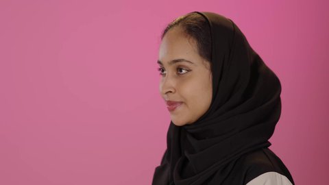 الإكثار من الدعاء في شهر رمضان، الاهتمام بالمظهر الخارجي والأناقة والأنوثة، مفهوم الاستقبال والترحيب، بورتريه مقرب من الجانب لامرأة عربية خليجية سعودية سمراء مبتسمه ترتدي الحجاب والزي الكاجوال تنظر إلى الاعلى ترفع يديها بايماءات الدعاء والتضرع, خلفية ملونه