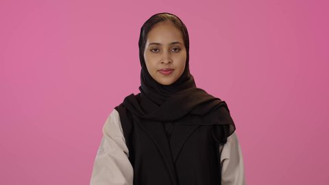 مفهوم الاستقبال والترحيب, التعارف و الصداقه وتكوين علاقات, إلقاء التحيه والسلام, بورتريه لشابة عربيه خليجيه سعودية سمراء ترتدي الحجاب و الزي الكاجوال تقوم بمد كفها للمصافحة، خلفية ملونه