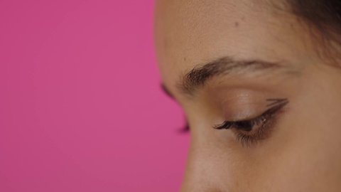 مفهوم الإهتمام بالجمال والبشرة، صالون تجميلي نسائي، ادوات مكياج تتوريال، بورترية مقرب من الجانب لامراة عربية خليجية سعودية سمراء تحمل (قلم المسكرة) لإبراز العين، التسويق لمنتجات التجميل، متجر بيع مستحضرات التجميل عبر الإنترنت