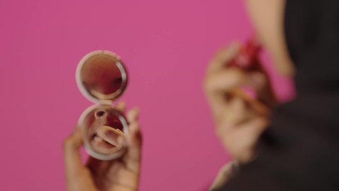 مستحضر تجميلي نسائي, جودة المنتج السعودي, مفهوم الاهتمام بالجمال والمظهر الخارجي, أدوات مكياج تتوريال, بورتريه مقرب لأيدي امرأة عربية سعودية خليجية سمراء محجبة تقوم بوضع أحمر الشفاه, خلفية ملونه