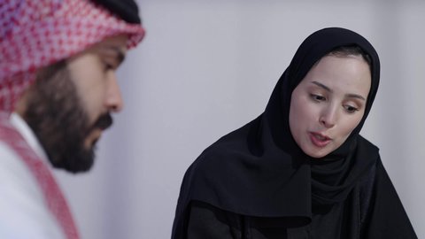 مكاتب و شركات خليجية، رجل عربي سعودي خليجي يرتدي الثوب التقليدي والشماغ  مع موظفه سعوديه يجلسون في المكتب داخل مقر الشركة ،مهنة ووظيفة سعوديه،مراجعة الخطط والاستراتيجيات والاتفاقيات، الوحدة والعمل الجماعي لتطوير الأعمال وحل المشكلات
