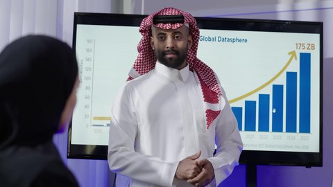 مهنة ووظيفة سعوديه،مراجعة الخطط والاستراتيجيات والاتفاقيات، الوحدة والعمل الجماعي لتطوير الأعمال وحل المشكلات، مكاتب و شركات خليجية، رجل عربي سعودي خليجي يرتدي الثوب التقليدي والشماغ مع موظفه سعوديه يجلس في المكتب داخل مقر الشركة