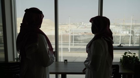 بيئة مريحة في الشركات السعوديه, شرح خطط و استراتيجيات المهام المطلوبة, تبادل النقاشات في مهام العمل, مهنة ووظيفة سعوديه, التعارف وبناء العلاقات الاجتماعية, رجل أعمال عربي خليجي سعودي خليجي يرتدي الثوب التقليدي والشماغ مع موظف يجلس داخل مقر الشركة
