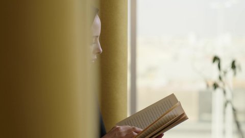 أماكن هادئة مريحة للدراسة، مفهوم الشغف بالقراءة,ممارسة هواية المطالعة,  امراة عربية خليجية سعودية محجبة ترتدي العباءة الملونة تمسك كتاب بيديها, الكتب و الروايات على المسلية