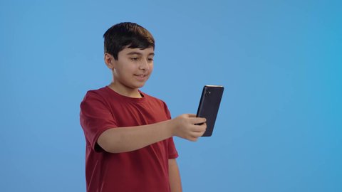 إجراء مكالمة فيديو ، التواصل مع الأصدقاء،استخدام الأطفال للتكنولوجيا الحديثة,  تصفح الإنترنت والمحادثات، ولد عربي خليجي سعودي يرتدي الزي الكاجوال يستخدم الجوال