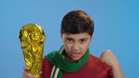 Sports matches and games, interaction and integration while watching the favorite team, gestures of joy and enthusiasm, passion for recreational activities, portrait of a Saudi Arabian Gulf boy holding the cup in his hand