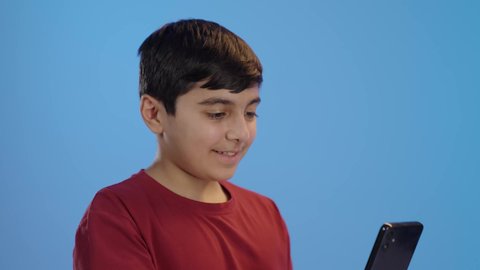 التواصل مع الأصدقاء،استخدام الأطفال للتكنولوجيا الحديثة,  تصفح الإنترنت والمحادثات، ولد عربي خليجي سعودي يرتدي الزي الكاجوال يستخدم الجوال، إجراء مكالمة فيديو