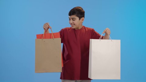 متعة التسوق في السعوديه، الاستفادة من عروض وتخفيضات الجمعة البيضاء، اقتناء المستلزمات والهدايا، ولد عربي خليجي سعودي يرتدي الزي الكاجوال يحمل بيده أكياس ورقية يرفع قبضته للاعلى دليل على الانجاز