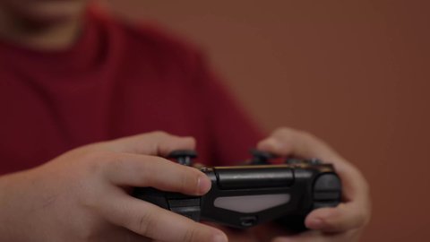 استخدام جهاز تكنولوجي تقني حديث ومتطور، قضاء وقت ممتع في ألعاب الفيديو الترفيهيه،إيماءات الاستمتاع والاندماج،  تصوير مقرب  لولد عربي خليجي سعودي يرتدي الزي الكاجوال يجلس على كرسي متحرك يحمل بيده عصا التحكم