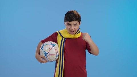 الشغف بالانشطة الترفيهية، المباريات والالعاب الرياضية,  التفاعل والاندماج بمشاهدة الفريق المفضل,ايماءات الفرح والحماس ,بورتريه لولد عربي سعودي خليجي يمسك بيده كرة قدم