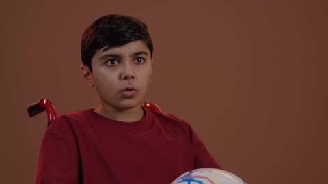 المباريات والالعاب الرياضية, ايماءات الفرح والحماس , التفاعل والاندماج بمشاهدة الفريق المفضل, بورتريه لولد عربي سعودي خليجي يجاس على كرسي متحرك يمسك بيده كرة قدم, الشغف بالانشطة الترفيهية