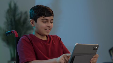 التواصل مع الأصدقاء، تصفح الإنترنت والمحادثات، التعليم الإلكتروني في السعوديه، استخدام الأطفال للتكنولوجيا الحديثة,  ولد عربي خليجي سعودي يجلس على كرسي متحرك ويستخدم التابلت، إجراء مكالمة فيديو