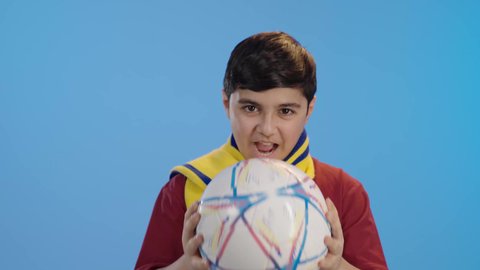 المباريات والالعاب الرياضية,  التفاعل والاندماج بمشاهدة الفريق المفضل,ايماءات الفرح والحماس ,بورتريه لولد عربي سعودي خليجي يمسك بيده كرة قدم, الشغف بالانشطة الترفيهية