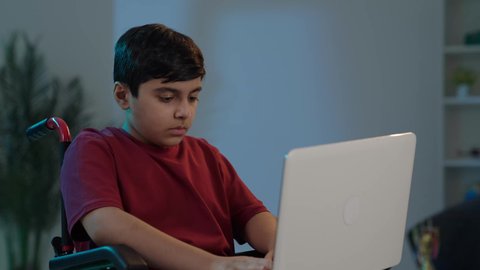 استخدام الأطفال للتكنولوجيا الحديثة, ولد عربي خليجي سعودي يجلس على كرسي متحرك ويستخدم الحاسوب المحمول، إجراء مكالمة فيديو، التواصل مع الأصدقاء، تصفح الإنترنت والمحادثات، التعليم الإلكتروني في السعوديه