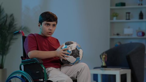 التفاعل والاندماج بمشاهدة الفريق المفضل,ايماءات الفرح والحماس ,  المباريات والالعاب الرياضية, بورتريه لولد عربي سعودي خليجي يجاس على كرسي متحرك يمسك بيده كرة قدم, الشغف بالانشطة الترفيهية