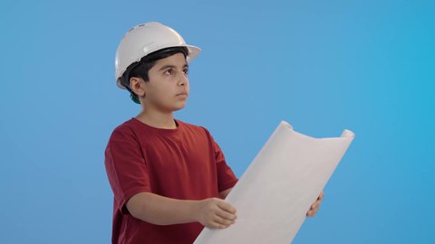 ولد عربي خليجي سعودي يرتدي خوذة الوقاية الخاصة بالعمل ، يمسك بيده مخطط هندسي ، اختيار مهنة مستقبلية ، تحديد المستقبل منذ الصغر ،مهن ووظائف هندسية