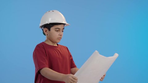 تحديد المستقبل منذ الصغر ،ولد عربي خليجي سعودي يرتدي خوذة الوقاية الخاصة بالعمل ، يمسك بيده مخطط هندسي ،اختيار  مهنة مستقبلية ، مهن ووظائف هندسية