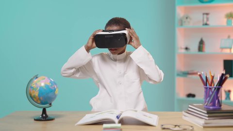 مدارس وأكاديميات متطوره، اتباع طرق تعليمية جديدة،  طالب عربي خليجي سعودي يرتدي الزي التقليدي يضع نظارات الواقع الافتراضي، جمع التعلم مع التكنولوجيا، إستخدام التقنيات الحديثه