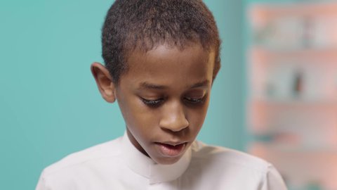 أجواء دراسية وتعليمية, ولد عربي خليجي سعودي يرتدي الزي التقليدي ينظر للاسفل بتركيز، مفهوم التعلم و المعرفه ، التعليم فى المملكه العربيه السعوديه